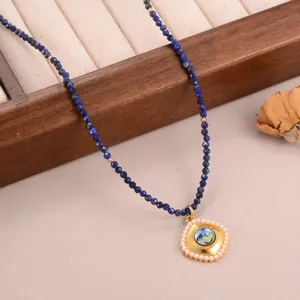 Close-up van een vintage kralenketting met gouden hanger en abalone schelp in het midden