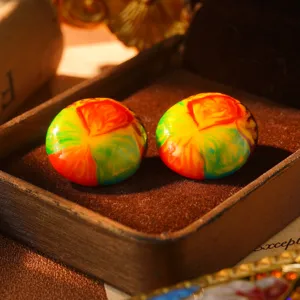 Macro view of colorful rainbow enamel earrings with marbled oil painting texture
