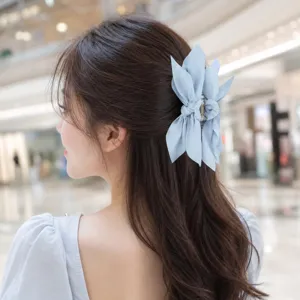 Close-up of a light blue butterfly bow hair claw clip on a woman's brown hair
