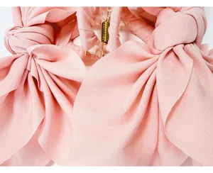 Close-up detail of a soft pink fabric bow hair claw clip showing woven texture.