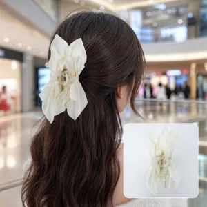 Detailed macro view of a large cream fabric bow hair claw clip for elegant hairstyles