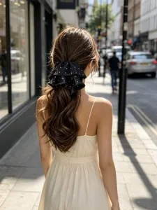Close-up of elegant black polka dot satin hair bow on a wavy low ponytail