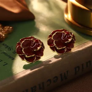 Detailaufnahme von dunkelroten Rosenohrringen mit goldenem Rand auf einem antiken Buch
