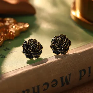 Nahaufnahme eleganter Vintage-Ohrstecker in Form einer schwarzen Rose mit Goldrand