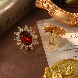 Vintage sunburst clip-on earrings featuring a large red gemstone and crystal details.