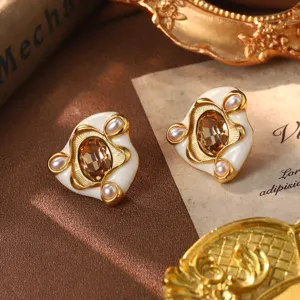 Close-up of luxury vintage earrings featuring white enamel, pearls, and amber crystal.
