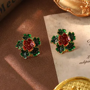 Macro detail of vintage red and green enamel flower earrings with a gold-plated finish