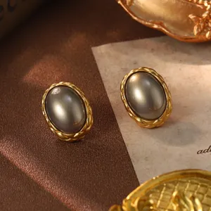 Macro view of vintage gold braided stud earrings featuring an elegant grey oval pearl detail