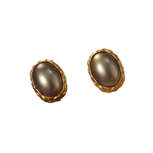 Vintage style oval earrings with grey pearl and gold braided frame on white background