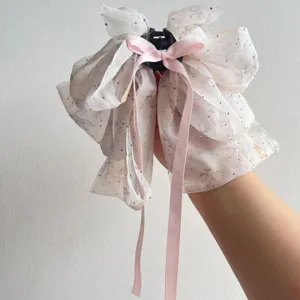 Detail showing multi-layered floral chiffon bow hair clip with long pink ribbons and rhinestones