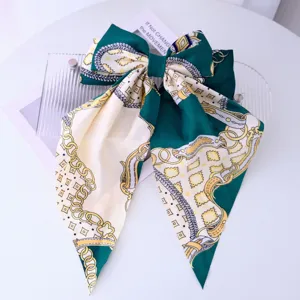 Macro view of a silky green bow hair clip featuring a classic gold chain and rope pattern