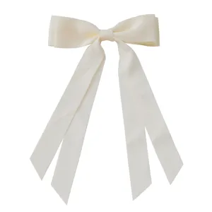 Close-up of a cream-colored large ribbon bow hair clip with long silk streamers