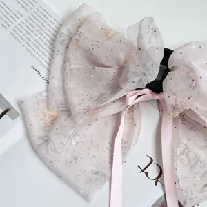 Close-up detail of floral chiffon bow hair claw clip with rhinestones and pink ribbons