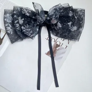 Close-up detail of a floral chiffon bow hair clip with elegant long streamers and rhinestones