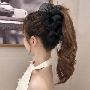 Detail view of large black mesh flower hair claw clip with delicate feather accents