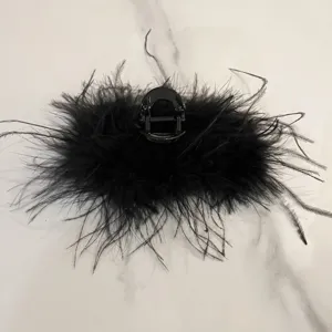 Close-up detail showing the soft texture of a large black ostrich feather hair claw clip.