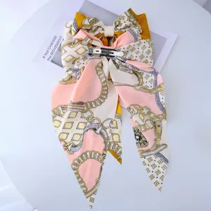 Back view of a large silky bow hair clip with elegant pink and yellow chain patterns.