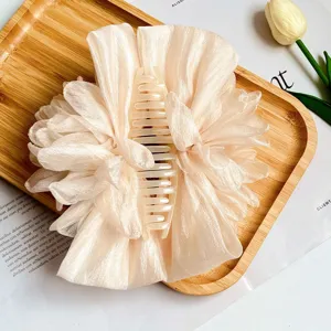 Dettaglio macro di un grande fermaglio per capelli con fiore di stoffa crema su legno