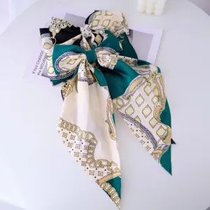 Close-up of large emerald green bow hair clip with Baroque chain print and long ribbons.