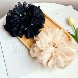 Dettaglio di grandi fermacapelli a fiori in tessuto 3D in nero e seta crema champagne