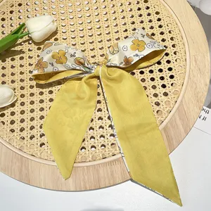 Detailed close-up of a vintage French floral pattern hair ribbon tied in a yellow bow knot