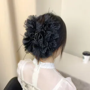 Detailansicht einer großen schwarzen Haarspange mit Federn und Stoffblumen im Haar.