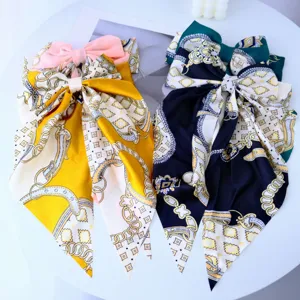 Detail shot of two silky bow hair clips with elegant chain prints in gold and navy colors.
