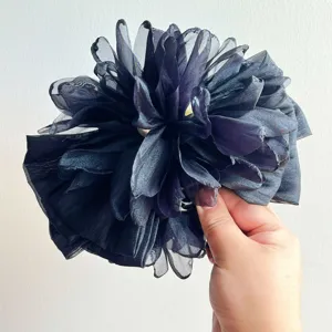 Primo piano di un fermaglio per capelli a fiore 3D in organza nera per uno stile elegante e raffinato