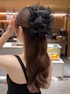Large black mesh cloud hair claw clip with elegant feather detail worn by a model