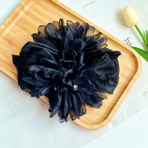 Vista dettagliata di una grande ed elegante molletta per capelli a fiore in tessuto nero