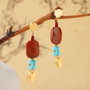 Macro detail of ethnic style handmade red natural stone and blue beaded earrings