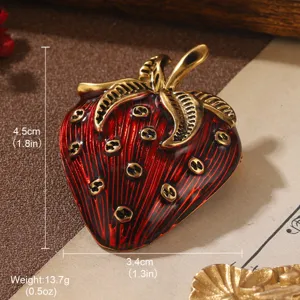 Close-up of a vintage red strawberry brooch with gold-tone leaf and size dimensions