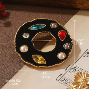 Close-up of vintage geometric brooch with black enamel, colorful gems, and pearls