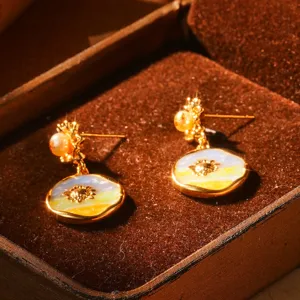 Détail de boucles d'oreilles vintage en émail français avec perles et motif tournesol