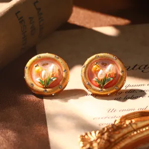 Macro view of French vintage enamel flower earrings with natural pearls and gold trim