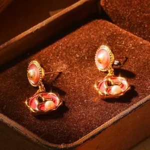 Gros plan de boucles d'oreilles vintage en émail avec perles dans un écrin marron