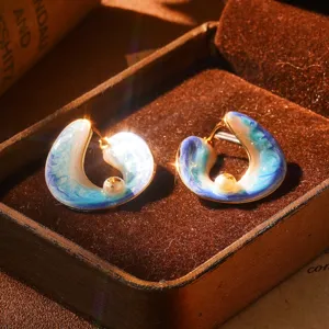 Gros plan sur des boucles d'oreilles émaillées vintage avec perles naturelles en boîte