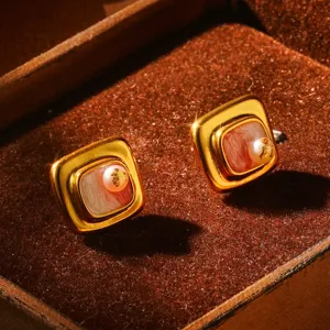 Détail rapproché de boucles d'oreilles vintage en émail français avec une petite perle délicate