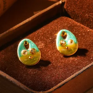 Gros plan sur boucles d'oreilles émail vintage avec perles naturelles et cristaux