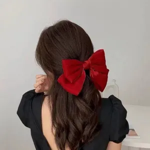 Detailed rear view of a large elegant red velvet bow hair clip on dark wavy hair