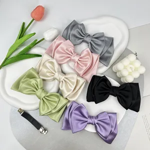Assorted colors of elegant satin bow hair clips displayed nicely on white decorative trays