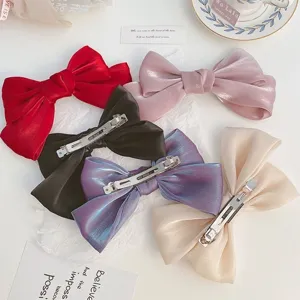 Various colors of shiny silk bow hair clips with metal barrettes shown on white background