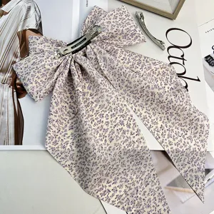 Gros plan d'une pince à cheveux nœud floral violet avec rubans et clip métal