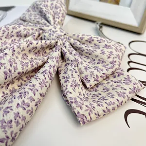 Gros plan d'une élégante pince à cheveux à nœud fleuri violet avec ressort clip