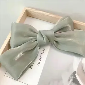 Macro detail of elegant sage green shiny silk bow hair clip with metallic luster finish