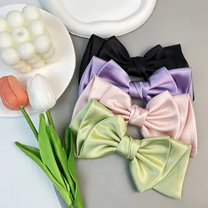 Detail view of multi-colored satin bow hair clips including pink, green, purple and black