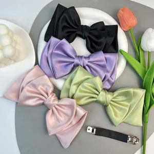 Detail of oversized satin bow hair clips in multiple colors with barrette base.