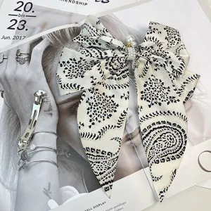 Detail of vintage satin bow hair clip featuring elegant pearls and paisley pattern.