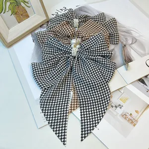 Close-up detail of vintage houndstooth bow hair clip with elegant pearl center decoration