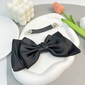 Close-up of elegant black satin bow hair clip showing texture and metal barrette back